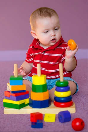 Bebê brincando com torre de argolas coloridas no Berçário do Colégio Antônio Villas Boas em Osasco.