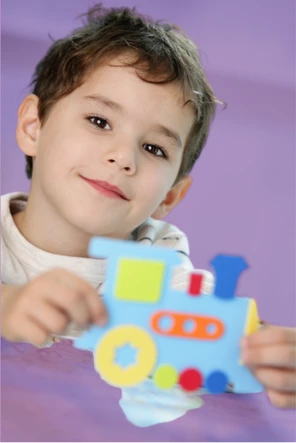 Aluno da Educação Infantil sorrindo e segurando um trem de brinquedo no Colégio AVB em Osasco.