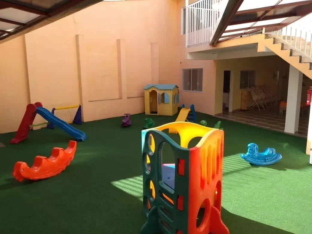 Playground externo seguro com grama sintética e brinquedos coloridos na Unidade Santo Antônio do Colégio Antônio Villas Boas.